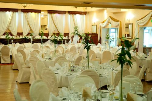 Darnley Lodge Hotel في Athboy: قاعة احتفالات بطاولات بيضاء وكراسي بيضاء