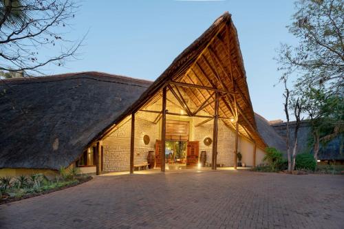 an exterior view of a building with a thatched roof at The David Livingstone Safari Lodge & Spa in Livingstone