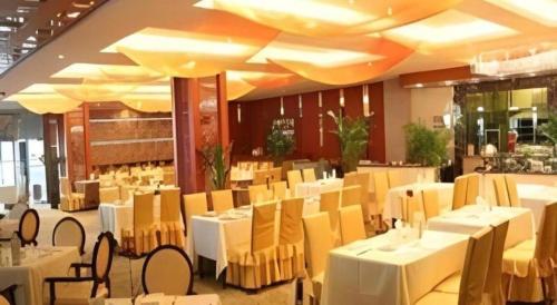 a restaurant with white tables and chairs in a room at Datong Tiangui International Hotel in Datong