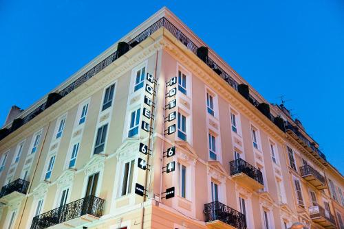 un bâtiment rose et blanc avec un ciel bleu en arrière-plan dans l'établissement Hotel 64 Nice, à Nice