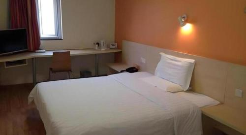 a bedroom with a bed and a desk with a computer at 7 Days Inn Qingdao Liaoyang West Road Xinye Plaza Metro Station in Qingdao
