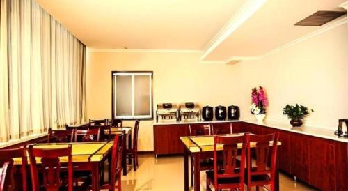 a dining room with tables and chairs and a kitchen at GreenTree Inn Xinjiang Uygur Autonomous Region Korla Bazhou Bus Terminal Beishan Road Express Hotel in Korla