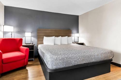 a bedroom with a bed and a red chair at Econo Lodge in Goose Creek