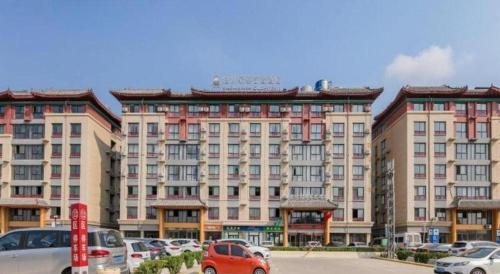 a large building with cars parked in a parking lot at GreenTree Inn Qufu High Speed Railway Station in Jining