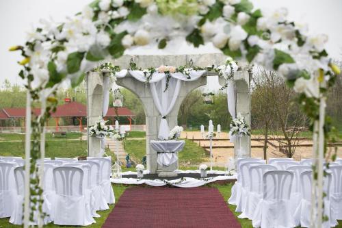 an aisle with white chairs and an arch with flowers at Hotel Kormorán in Šamorín