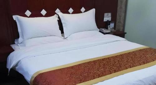 a large bed with white sheets and pillows at Shell Hotel Taiyuan South Railway Station New Southeast Bus Station in Taiyuan