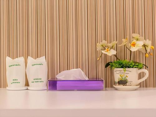 a table with three products and a vase with flowers at Orchid Residence in Nakhon Si Thammarat