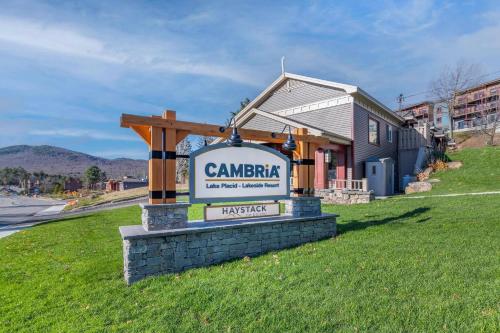 a sign in the grass in front of a building at Cambria Hotel Lake Placid - Lakeside Resort in Lake Placid