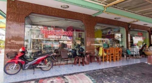 a motorcycle parked in front of a store with tables and chairs at OYO 75314 Mountain Beach in Prachuap Khiri Khan