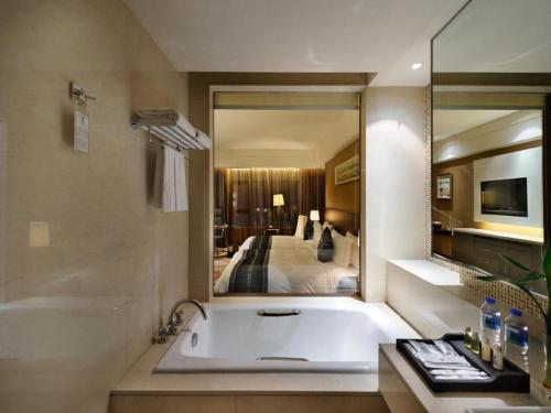a bathroom with a bath tub and a large mirror at Putian Depo Hotel in Putian