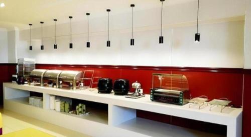 a kitchen with red walls and white counter tops at GreenTree Inn Jiangsu Xuzhou Jinshan Bridge Building Jinqiao Road Express Hotel in Xuzhou