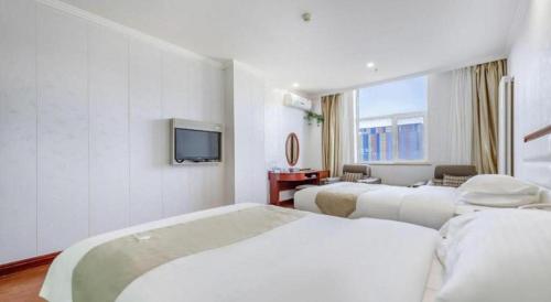 a hotel room with two beds and a television at GreenTree Inn Yinchuan Pedestrian Street East Liqun Street Express Hotel in Yinchuan