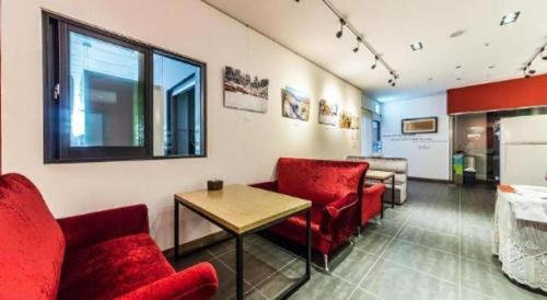 a waiting room with red chairs and a table at Line Plus Hotel in Gimpo