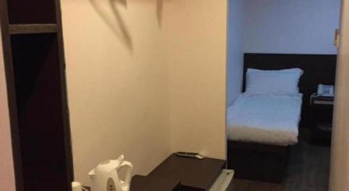 a small bedroom with a bed and a table at Metroplace Olympic in Hong Kong