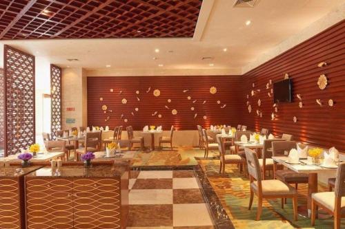 a restaurant with tables and chairs in a room at New Century Hotel Putuo Zhoushan in Zhoushan