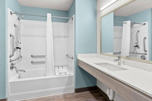 a bathroom with a tub and a sink and a shower at WoodSpring Suites Tucson Medical Center in Tucson