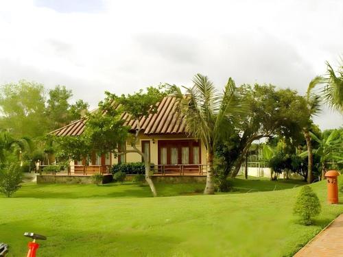 a house with a green lawn and trees at Can Gio Resort in Can Gio