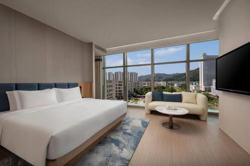 珠海市にあるDays Hotel by Wyndham Zhuhai Jinwanの大きな白いベッドとソファのある寝室
