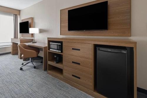 a hotel room with a television and a desk with a chair at La Quinta Inn & Suites by Wyndham Phoenix West Glendale in Phoenix