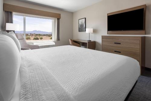 a bedroom with a large white bed and a flat screen tv at La Quinta Inn & Suites by Wyndham Phoenix West Glendale in Phoenix