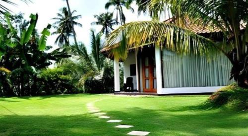 a house with a green lawn in front of it at Brook Boutique in Sigiriya