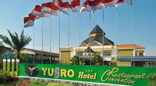 a hotel sign with flags in front of a building at Yusro Hotel Restaurant & Convention in Jombang