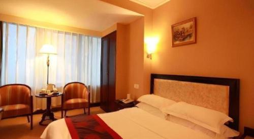 a hotel room with a bed and a table and chairs at Dalian Bohai Pearl Hotel in Dalian