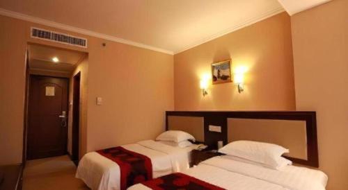 a hotel room with two beds and a door at Dalian Bohai Pearl Hotel in Dalian