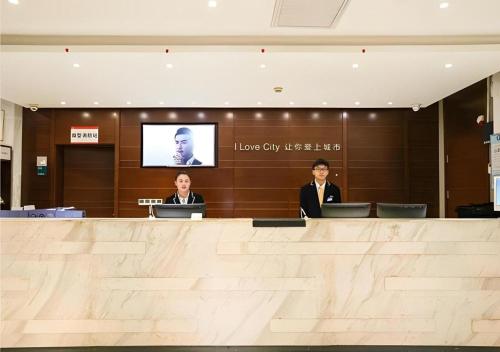 two people sitting at a counter in a lobby at City Comfort Inn Wuhan High Speed Railway Station in Wuhan