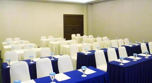 a room with blue and white tables and white chairs at Zenith Hotel in Kendari