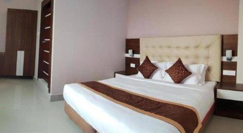 a bedroom with a large bed with white sheets and pillows at Hotel Gajur Palace in Itahari