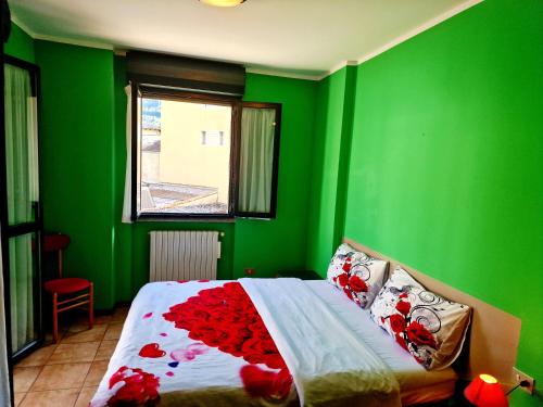 a green bedroom with a bed with red flowers on it at BERNINA STATION CENTRE APARTMENT 4 - Tirano in Tirano