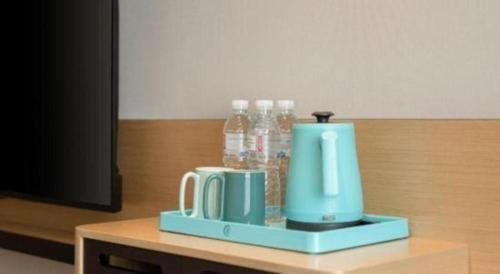 a table with two mugs and bottles of water at City Comfort Inn Nanning Guangxi University Xiuling Road Metro Station in Nanning