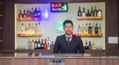 a man is sitting at a bar in a bar at Hotel Gajur Palace in Itahari