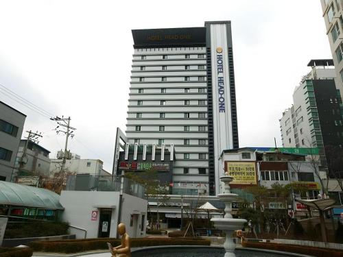 a woman walking in front of a tall building at Hotel Head-One in Uijeongbu
