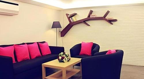 a living room with a blue couch and pink pillows at Iroom Hotel in Surat Thani