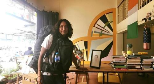 a man standing in front of a table with a bottle of water at Oldie and Sleepy Hostel in Udon Thani