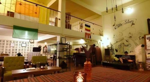 a living room with people sitting in chairs and a room at Oldie and Sleepy Hostel in Udon Thani