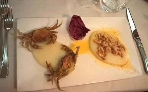 a plate of food with crabs and a pickle on a table at Hotel Villa Monica in Prata di Pordenone