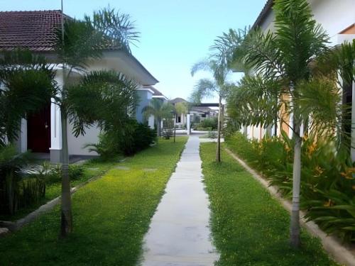 a walkway between two houses with palm trees at The Luxio Hotel in Sorong