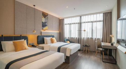 a hotel room with two beds and a desk at Home Inn Selected Xiamen University Zhongshan Road in Xiamen