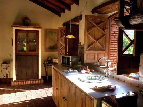 a kitchen with wooden cabinets and a sink and a counter at Tranquil Riverside Retreat in Alájar