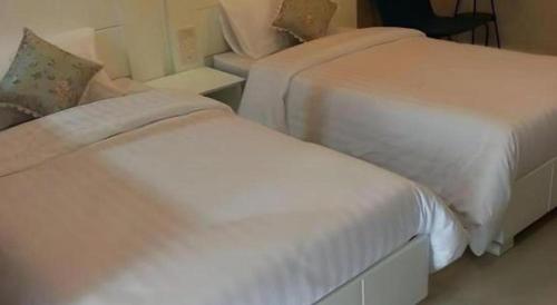 a bedroom with two beds and a chair at Waenpetch place Hotel in Ubon Ratchathani