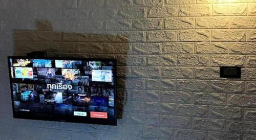 a tv hanging on a brick wall at Near beach hostel in Bang Tao Beach