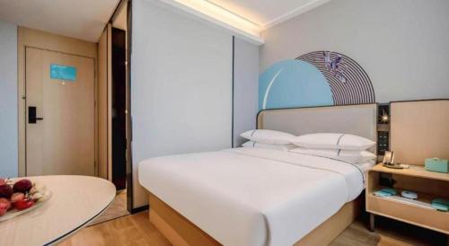 a bedroom with a large white bed and a bowl of fruit at City Comfort Inn Nanning Guangxi University in Nanning