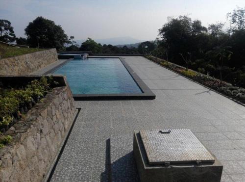 a swimming pool with a bench next to a stone wall at Fafa Hill Hotel and Resort in Bogor