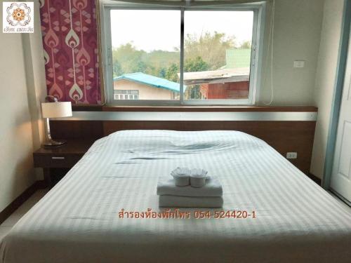 a bed in a room with a window and a bed sidx sidx sidx at Huern Che Ta One Hotel in Phrae