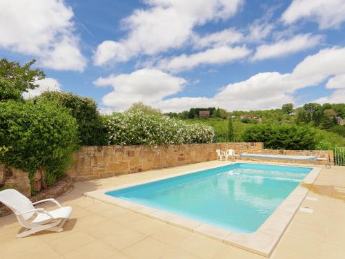 a swimming pool with two chairs and a stone wall at Heritage Cottage with Pool in Badefold d Ans in Badefols-dʼAns