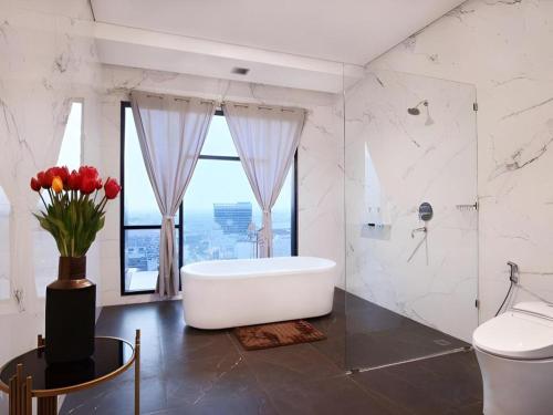 a white bathroom with a tub and a vase of flowers at The Bono Hotel Pekanbaru in Pekanbaru
