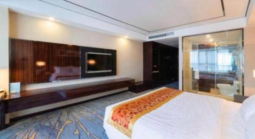 a hotel room with a large bed and a tv at Ramada by Wyndham Wuhu in Wuhu
